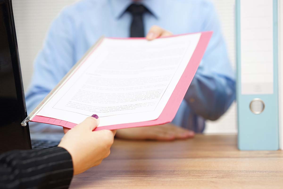 détail d'un certificat de travail qu'une personne tend à une autre personne